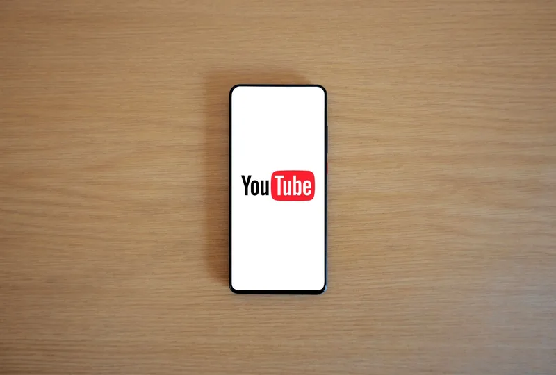 Close-up of a hand holding a smartphone displaying the YouTube app on screen